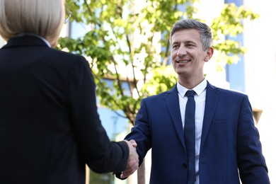 Photo of International relations. Diplomats shaking hands during meeting outdoors