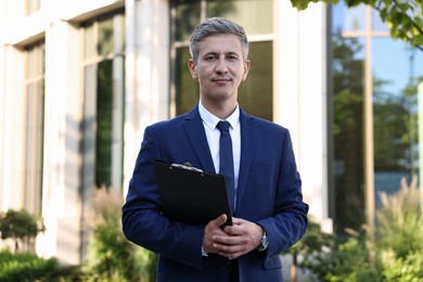 Photo of International relations. Diplomat with clipboard in suit outdoors