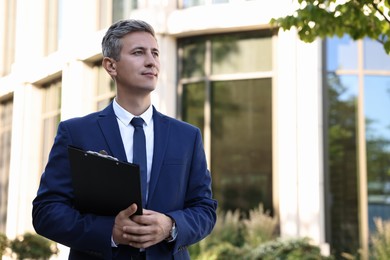 Photo of International relations. Diplomat with clipboard outdoors, space for text