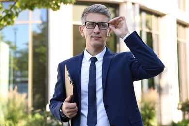 Photo of International relations. Diplomat with clipboard in suit outdoors