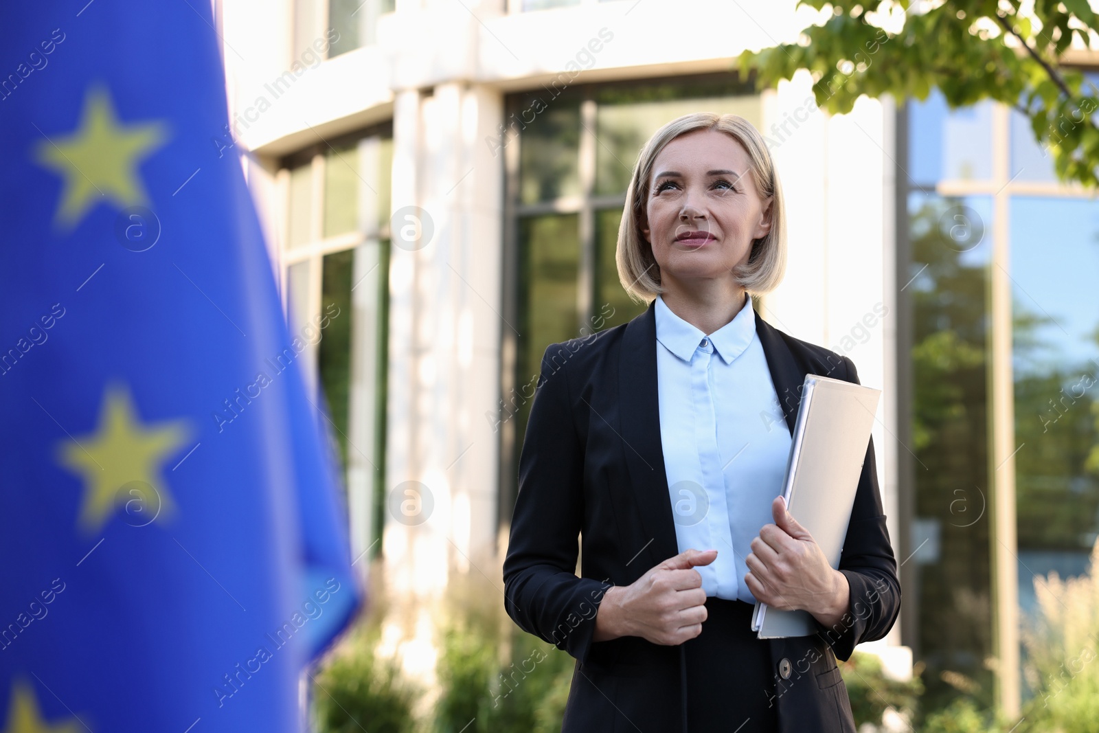 Photo of International relations. Diplomat with clipboard near flag of European Union outdoors