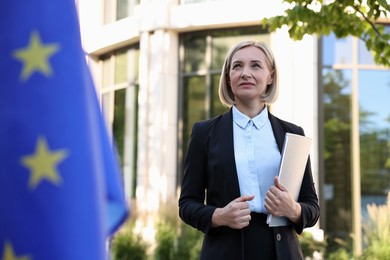 International relations. Diplomat with clipboard near flag of European Union outdoors