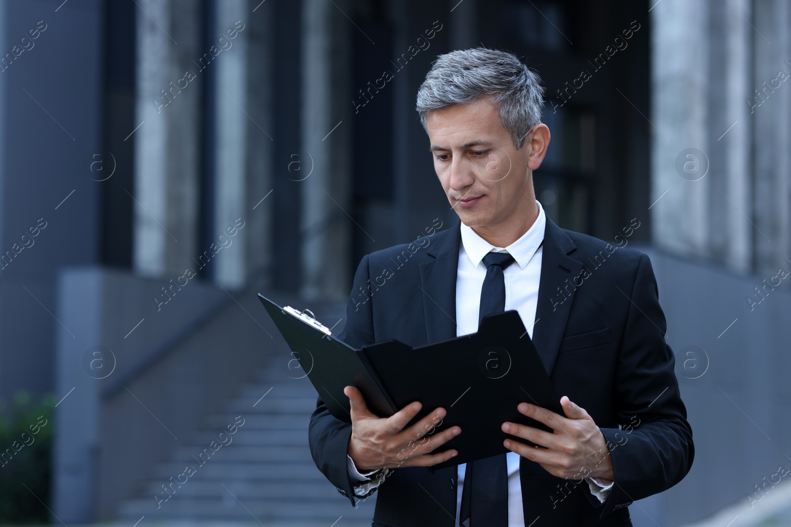 Photo of International relations. Diplomat with clipboard in suit outdoors, space for text