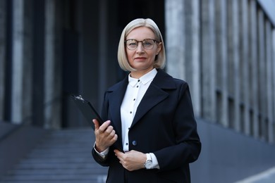 Photo of International relations. Diplomat with clipboard in suit outdoors