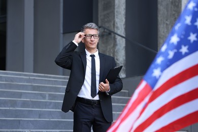 International relations. Diplomat with clipboard near flag of USA outdoors