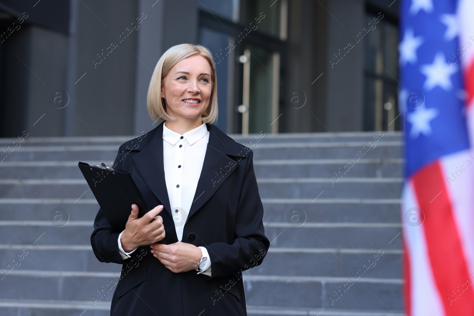 Photo of International relations. Diplomat with clipboard near flag of USA outdoors