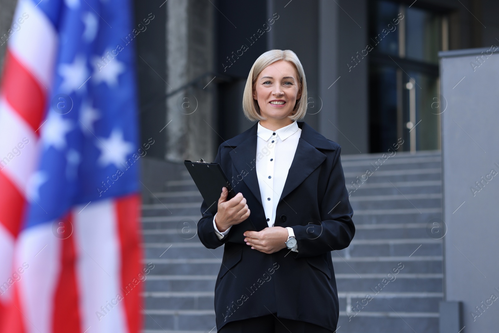 Photo of International relations. Diplomat with clipboard near flag of USA outdoors