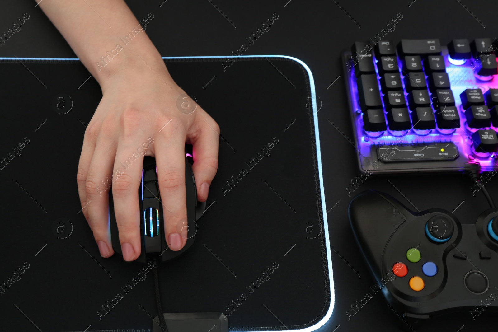 Photo of Gamer using modern wired computer mouse at dark table, above view