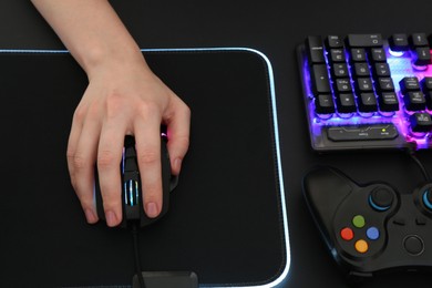 Photo of Gamer using modern wired computer mouse at dark table, above view