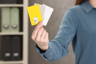 Photo of Woman holding SIM cards indoors, closeup view