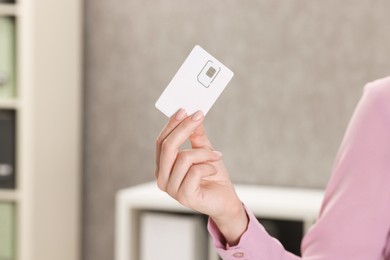 Photo of Woman holding SIM card indoors, closeup view