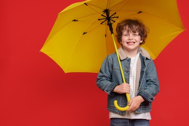 Little boy with yellow umbrella on red background