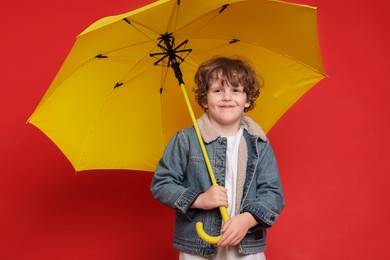 Little boy with yellow umbrella on red background