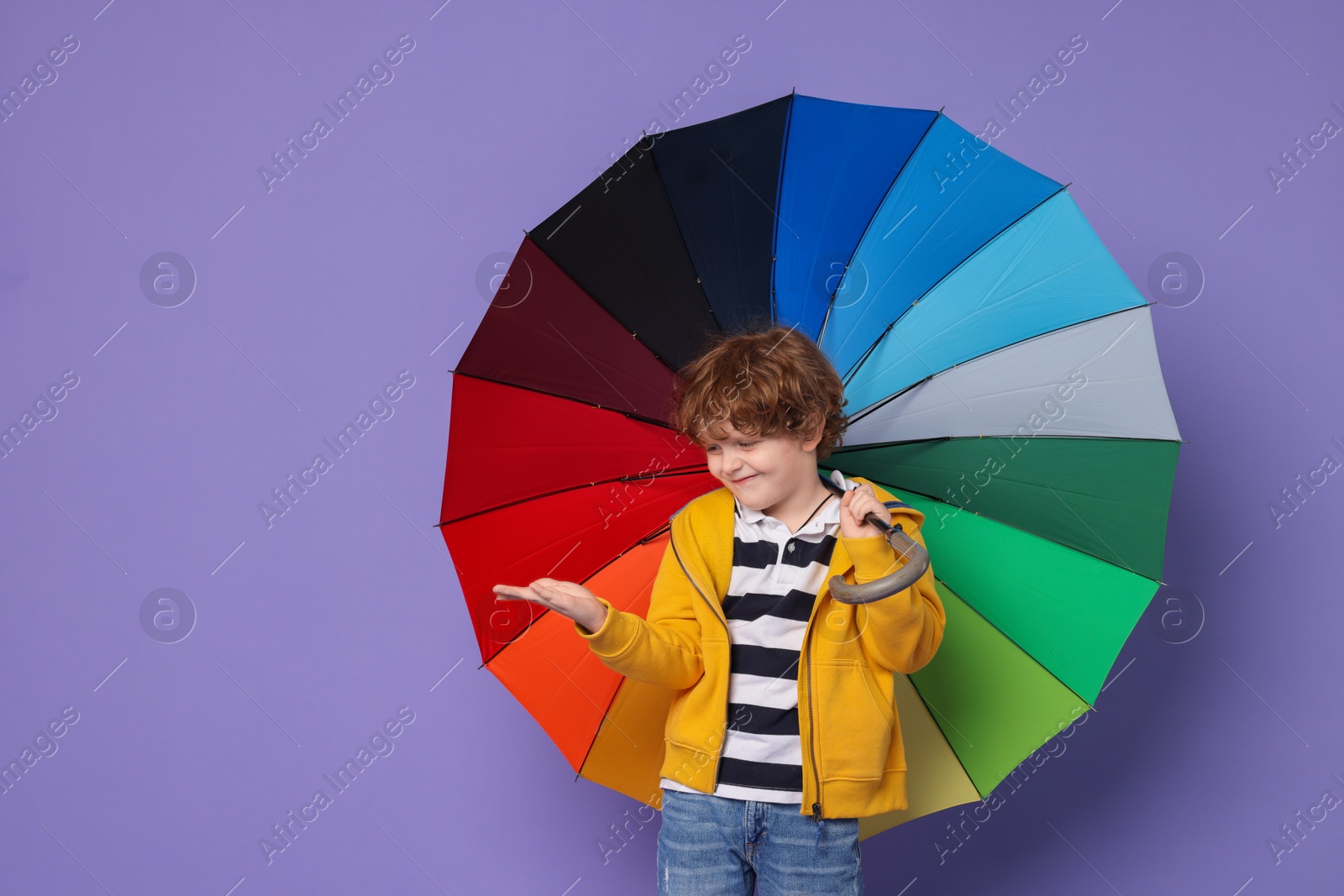 Photo of Little boy with rainbow umbrella on purple background, space for text