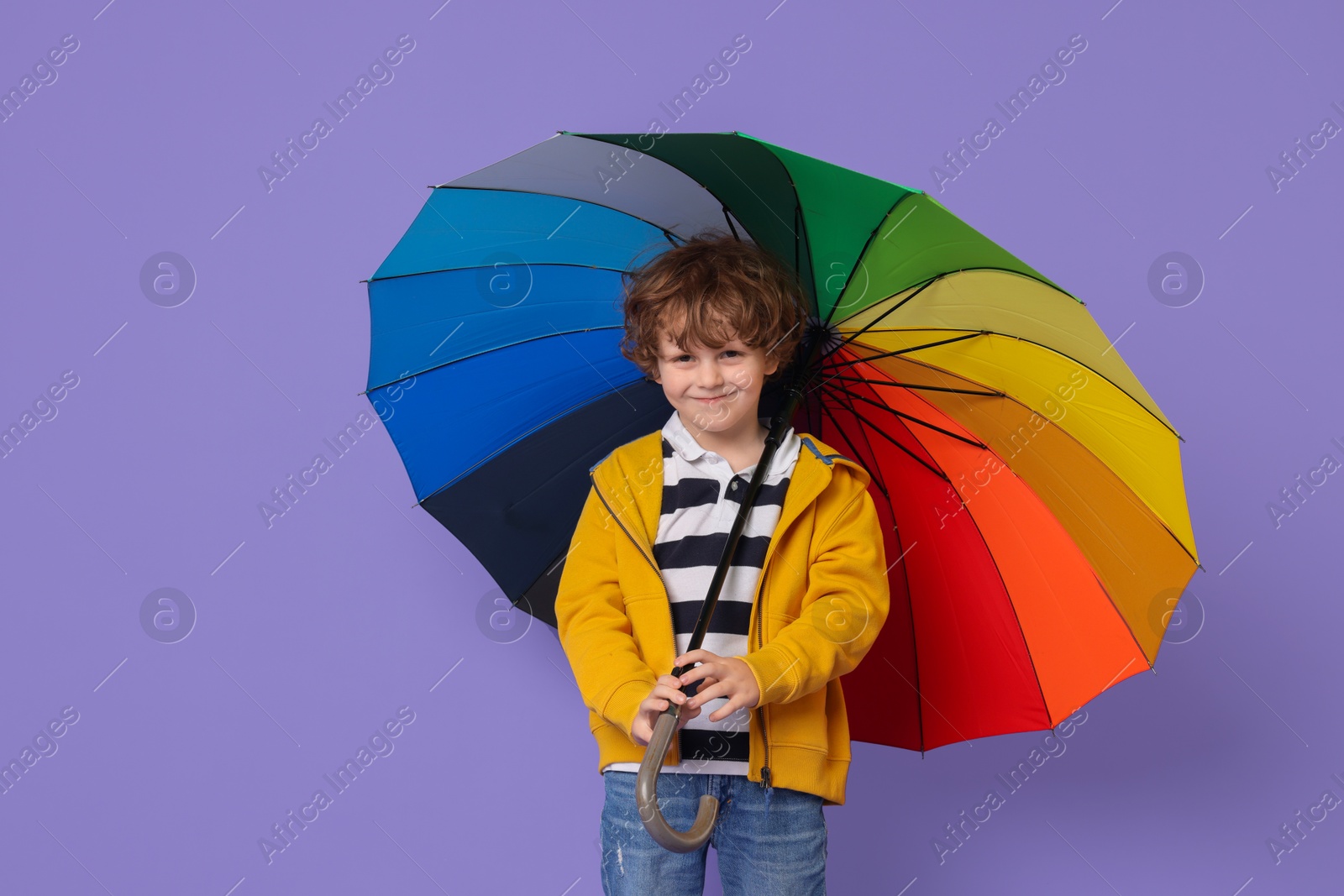 Photo of Little boy with rainbow umbrella on purple background