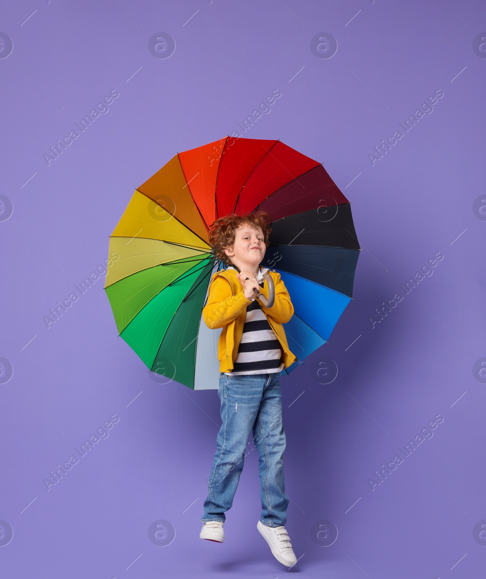 Photo of Little boy with rainbow umbrella on purple background