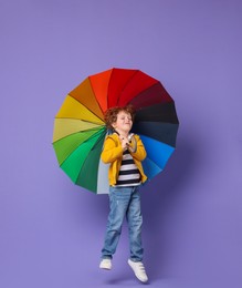 Photo of Little boy with rainbow umbrella on purple background