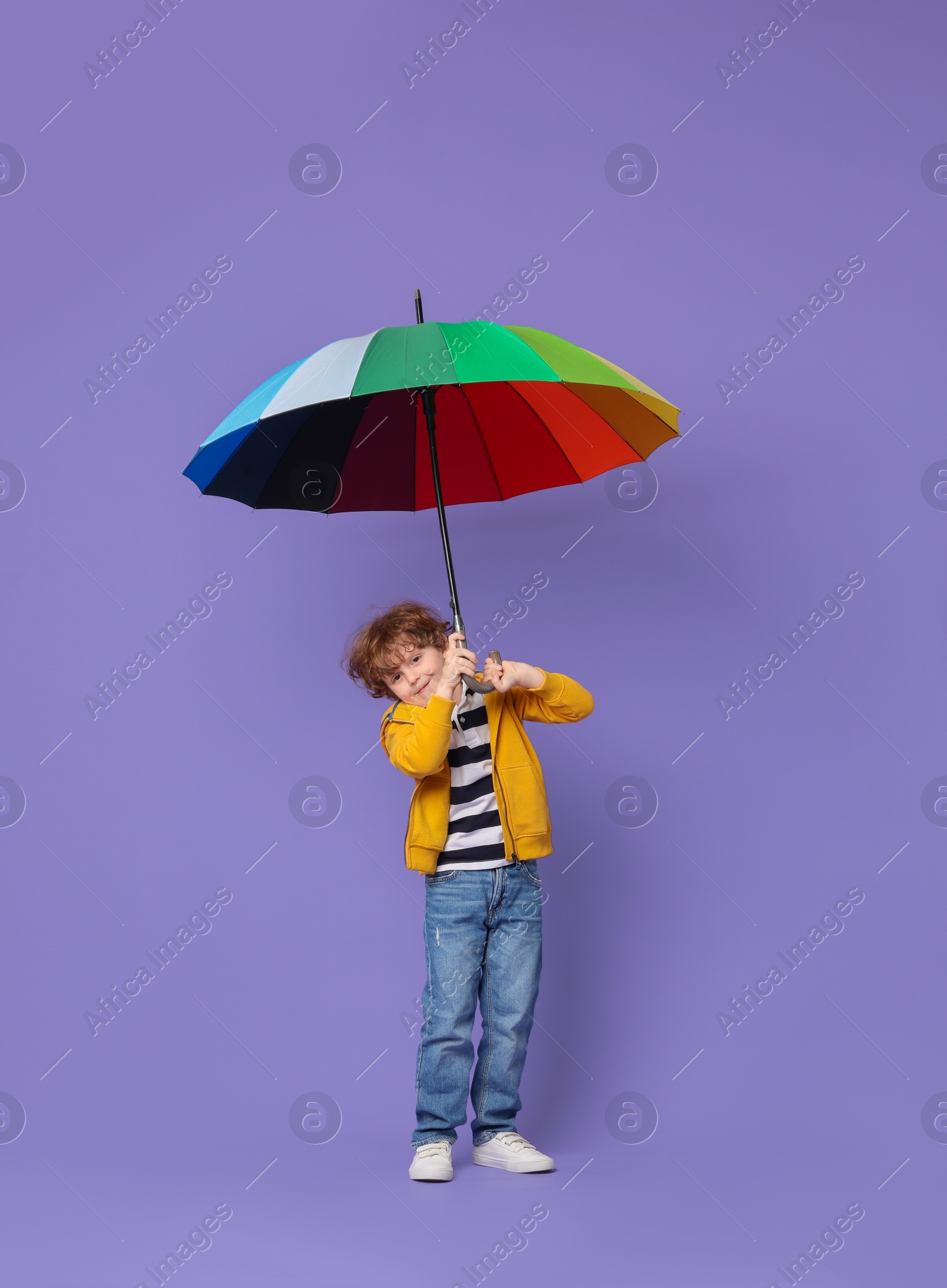 Photo of Little boy with rainbow umbrella on purple background