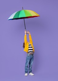 Photo of Little boy with rainbow umbrella on purple background