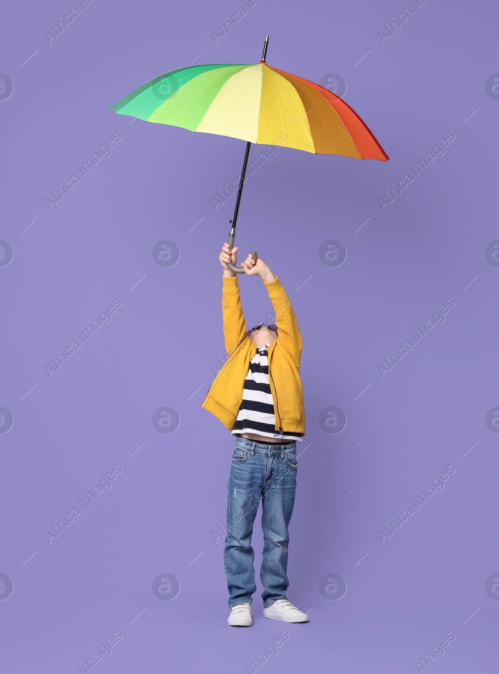 Photo of Little boy with rainbow umbrella on purple background