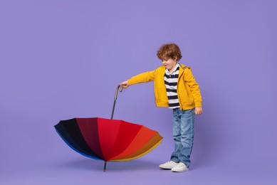 Little boy with rainbow umbrella on purple background