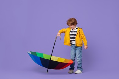 Little boy with rainbow umbrella on purple background