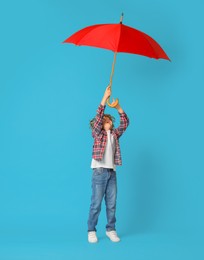 Photo of Little boy with red umbrella on light blue background, space for text