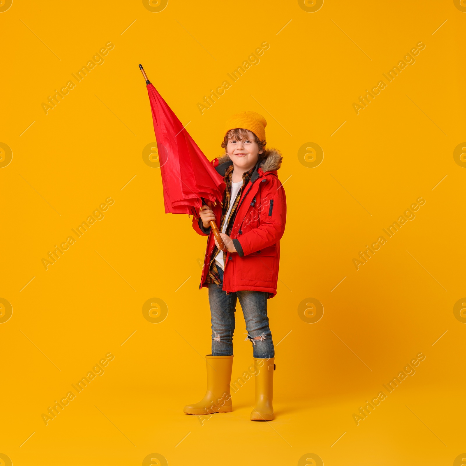 Photo of Little boy with red umbrella on orange background