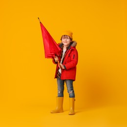 Photo of Little boy with red umbrella on orange background