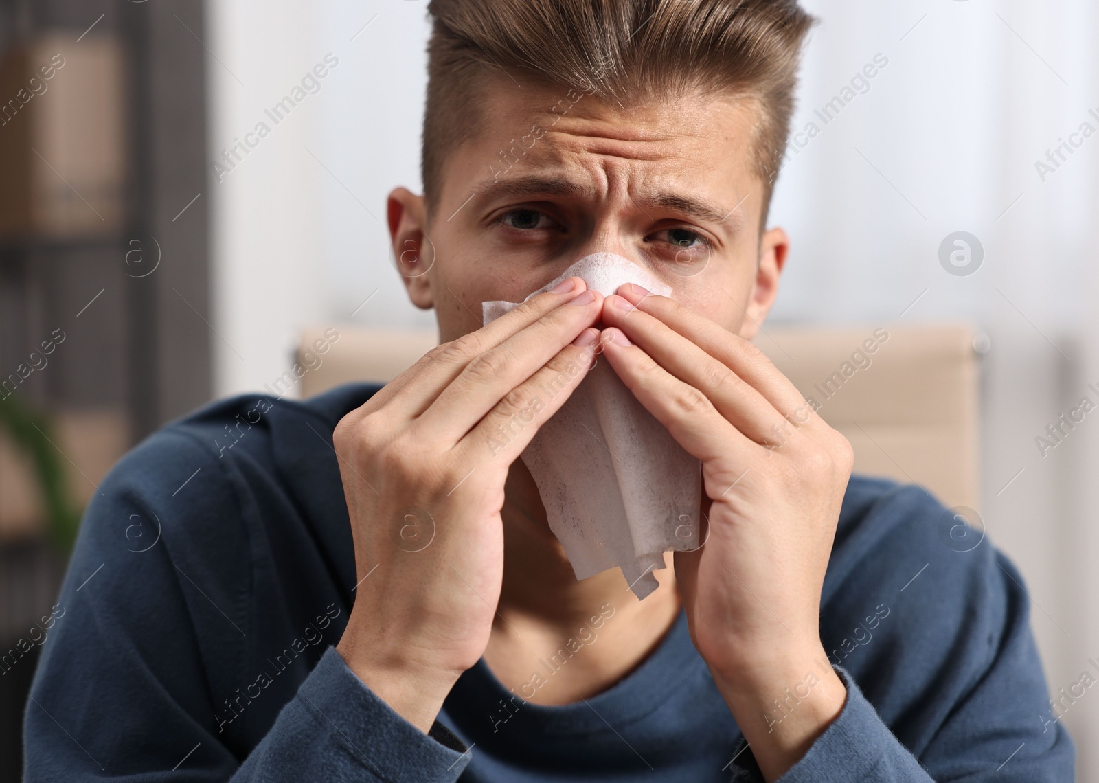 Photo of Young man with tissue suffering from sinusitis indoors