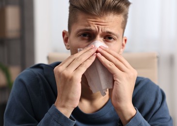 Photo of Young man with tissue suffering from sinusitis indoors