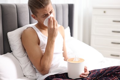 Photo of Young man with tissue suffering from sinusitis in bed at home