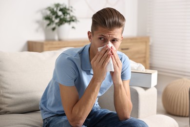 Young man with tissue suffering from sinusitis at home