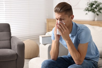 Young man with tissue suffering from sinusitis at home