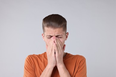 Young man suffering from sinusitis on light grey background