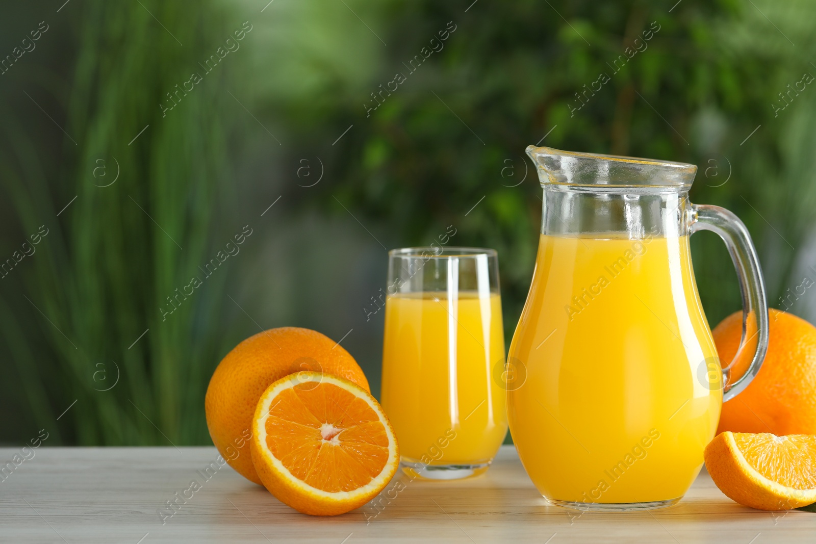 Photo of Tasty orange juice and fresh fruits on white wooden table outdoors. Space for text