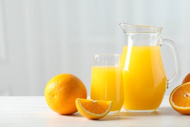 Photo of Tasty orange juice and fresh fruits on white wooden table. Space for text