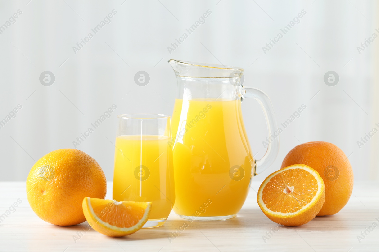 Photo of Tasty orange juice and fresh fruits on white wooden table