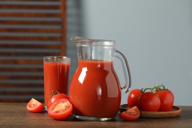 Photo of Tasty tomato juice in jug, glass and vegetables on wooden table