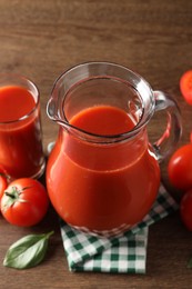 Photo of Tasty tomato juice in jug, glass and vegetables on wooden table, closeup