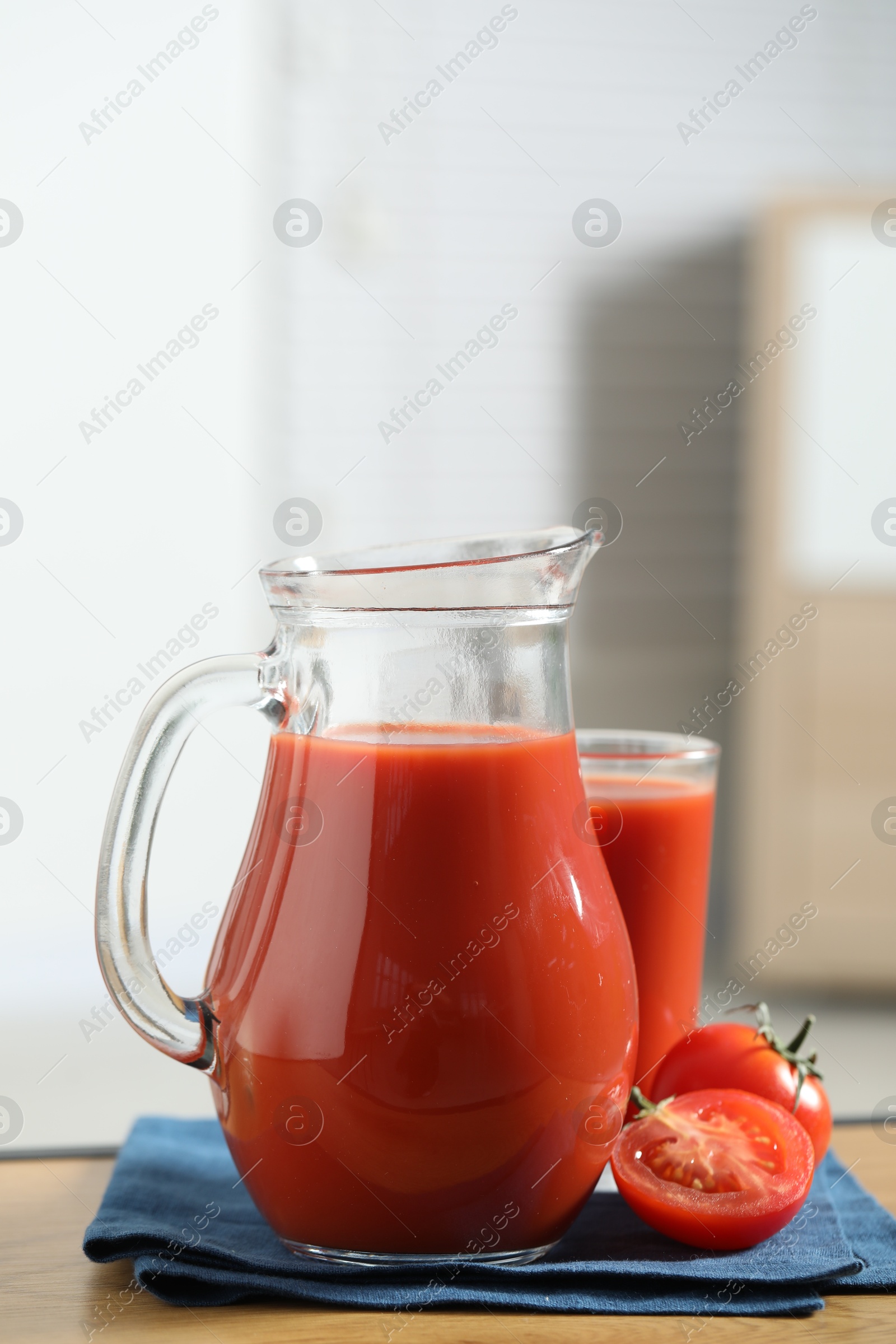 Photo of Tasty tomato juice in jug, glass and vegetable on wooden table indoors