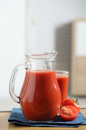 Photo of Tasty tomato juice in jug, glass and vegetable on wooden table indoors