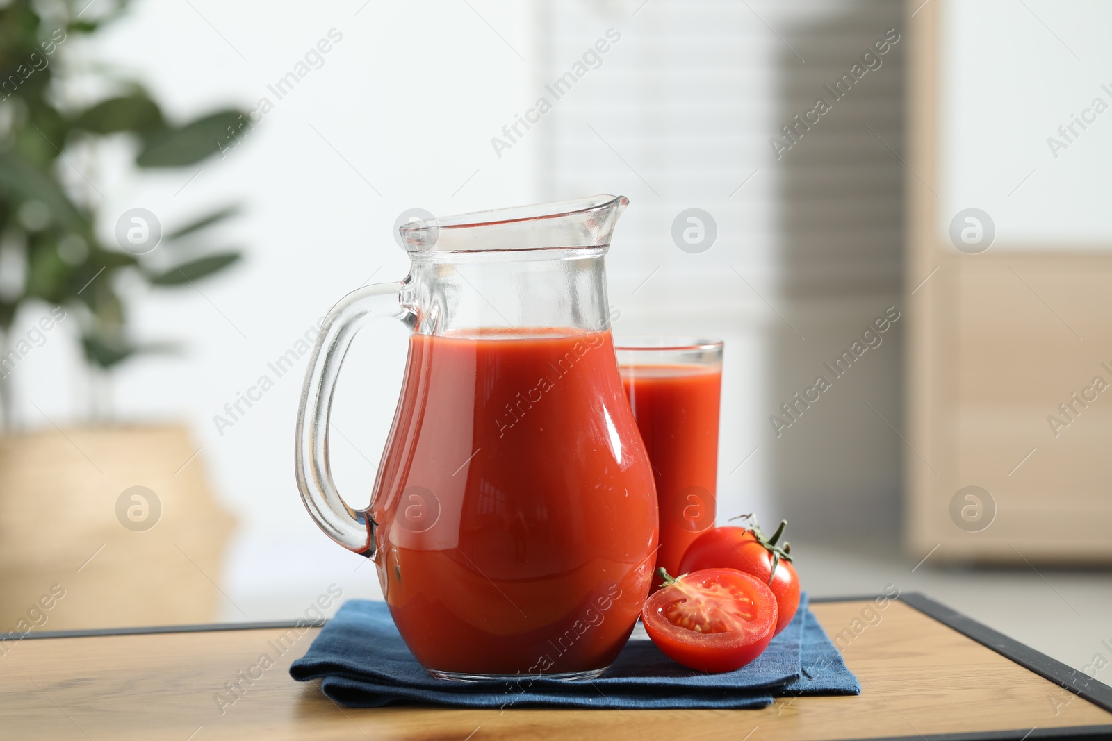 Photo of Tasty tomato juice in jug, glass and vegetable on wooden table indoors