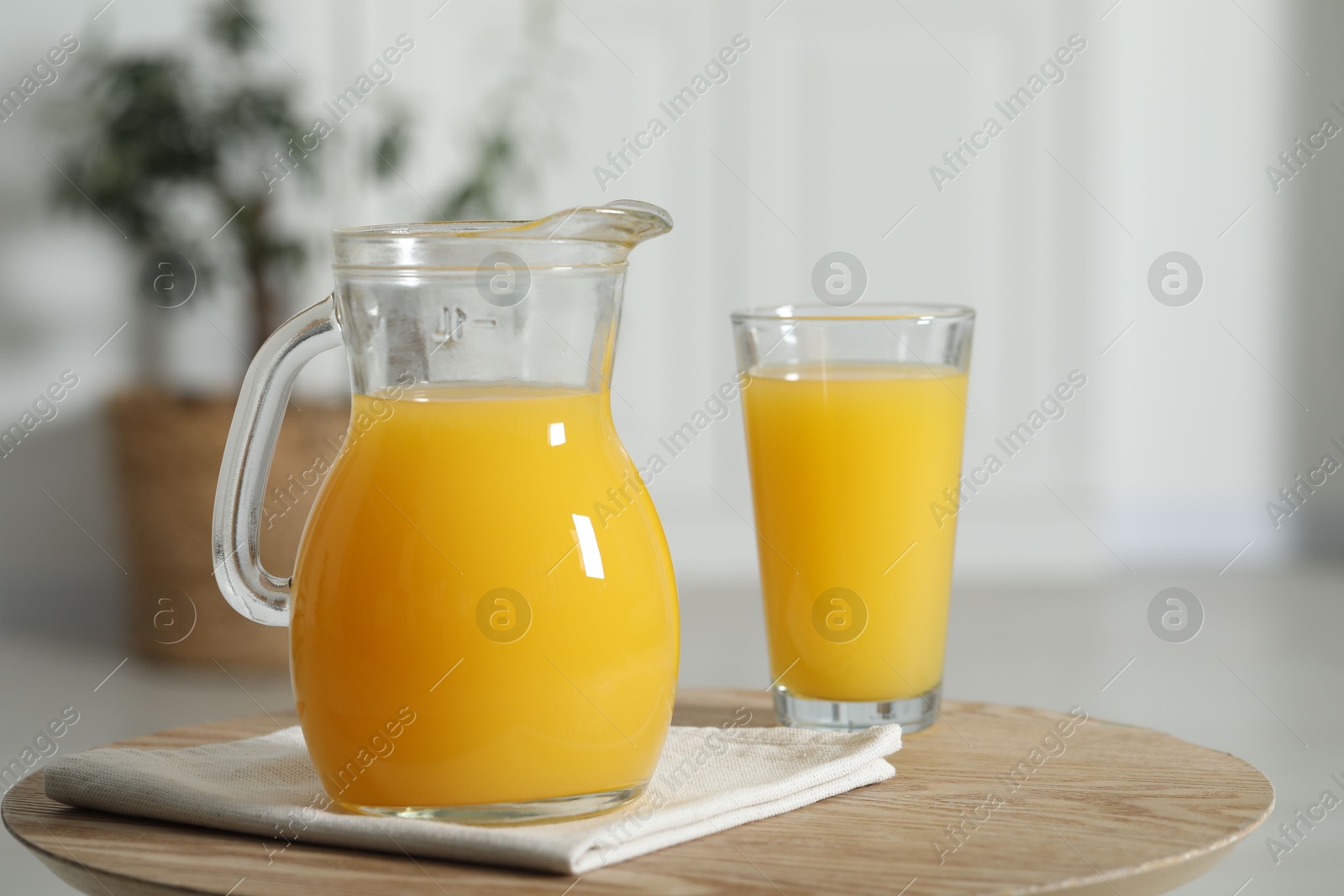 Photo of Tasty orange juice in jug and glass on wooden table