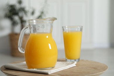 Tasty orange juice in jug and glass on wooden table