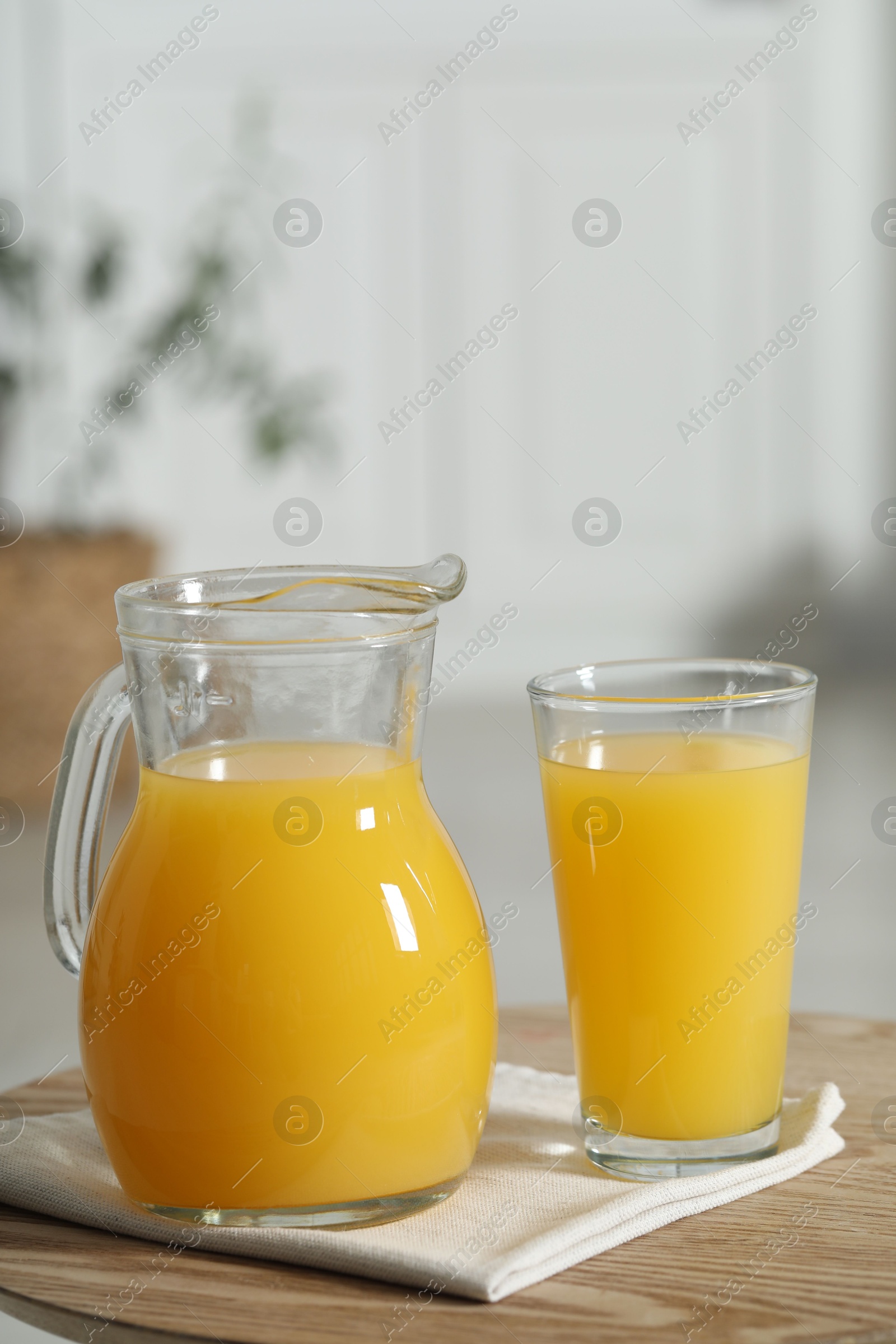 Photo of Tasty orange juice in jug and glass on wooden table