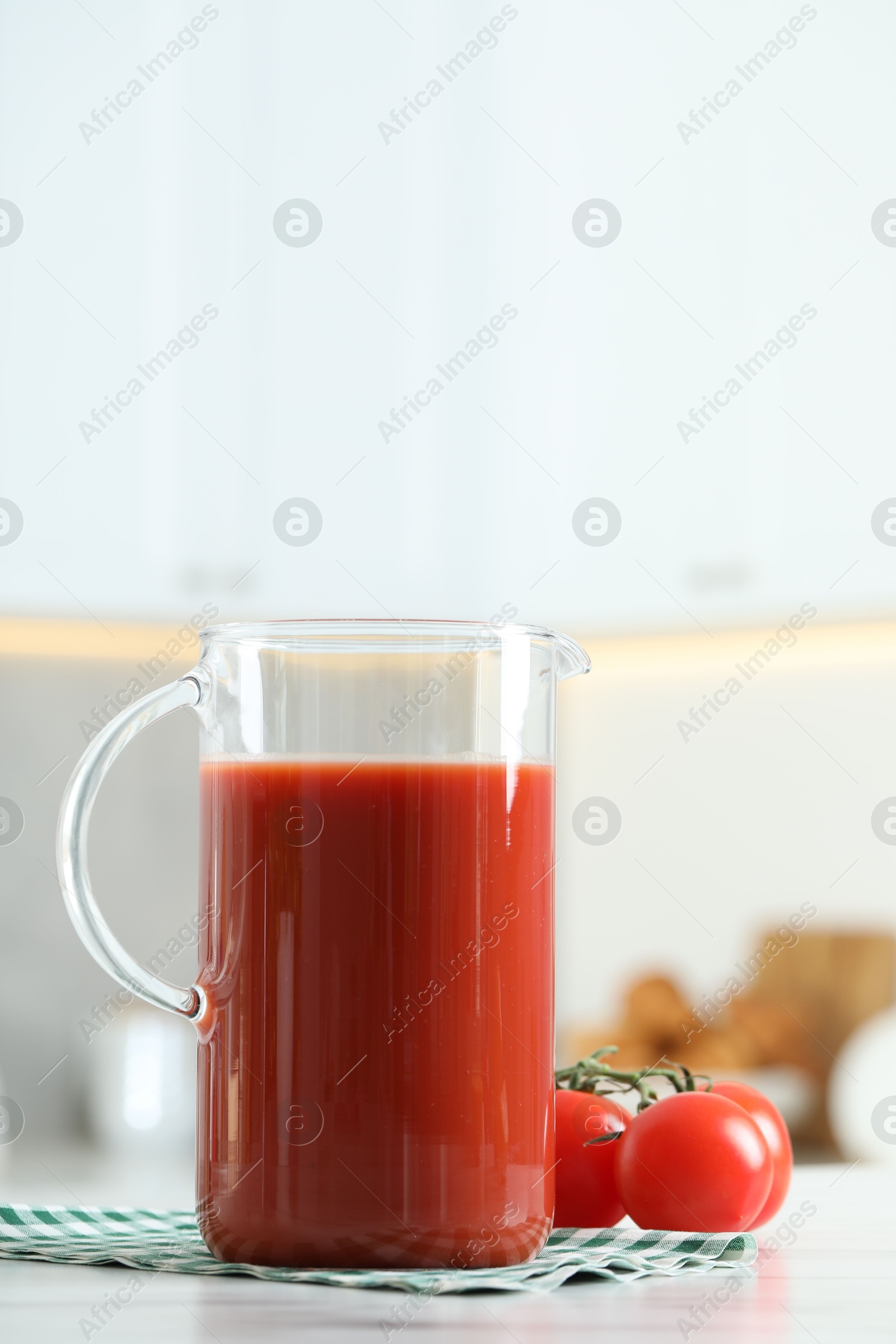 Photo of Tasty tomato juice in jug and vegetables on white table. Space for text