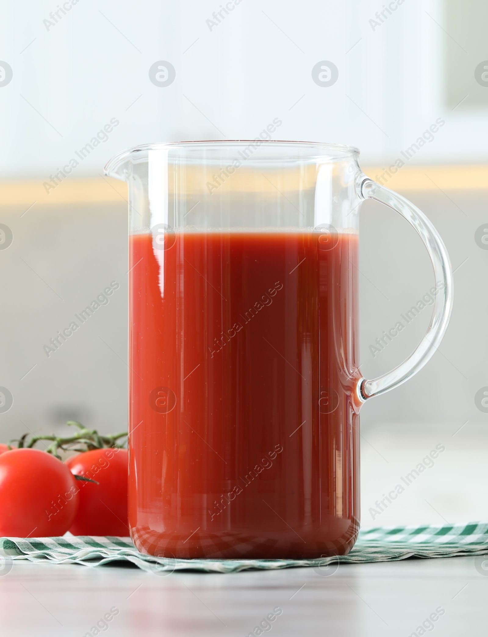 Photo of Tasty tomato juice in jug and vegetables on white table