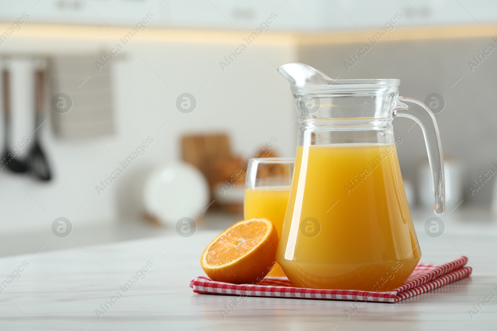 Photo of Tasty orange juice in jug, glass and citrus fruit on white marble table. Space for text