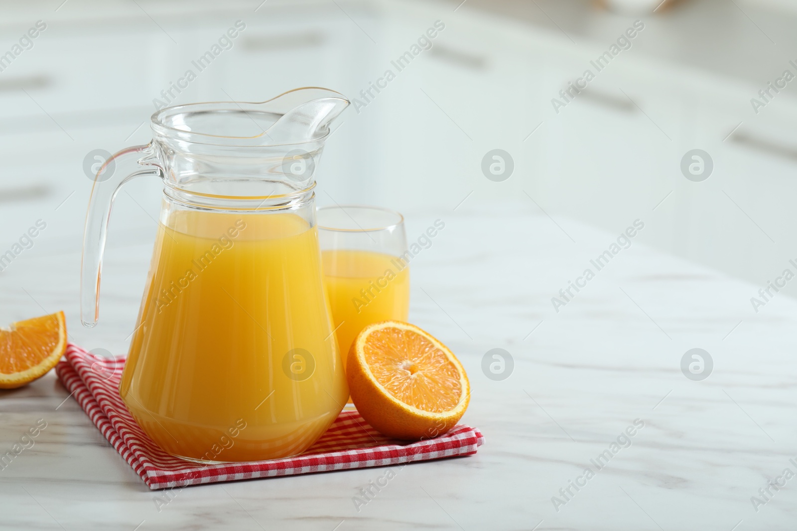 Photo of Tasty orange juice in jug, glass and citrus fruit on white marble table. Space for text